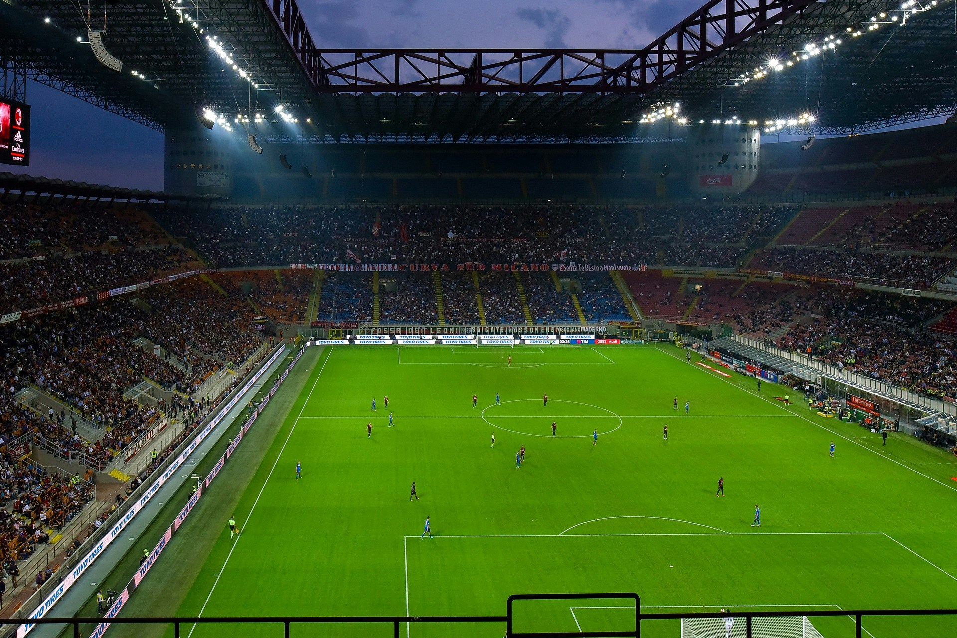 Football match at San Siro Stadium, Milan, with players on the field and spectators in the stands.