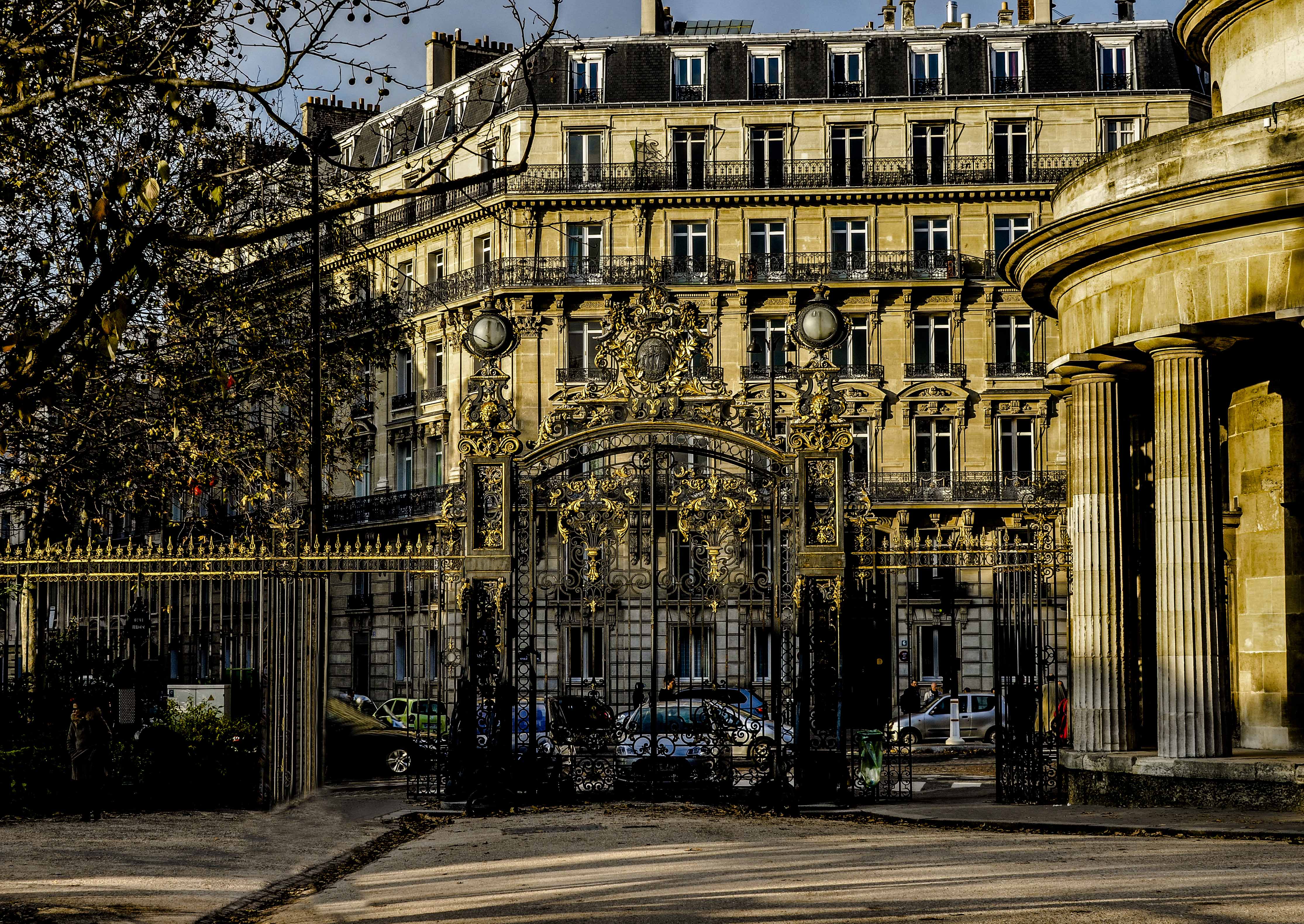Ornate entrance gate of Parc Monceau in Paris with historic building in background.