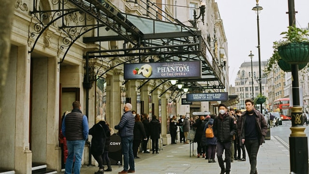 people standing in a ticket queue outside a london theatre