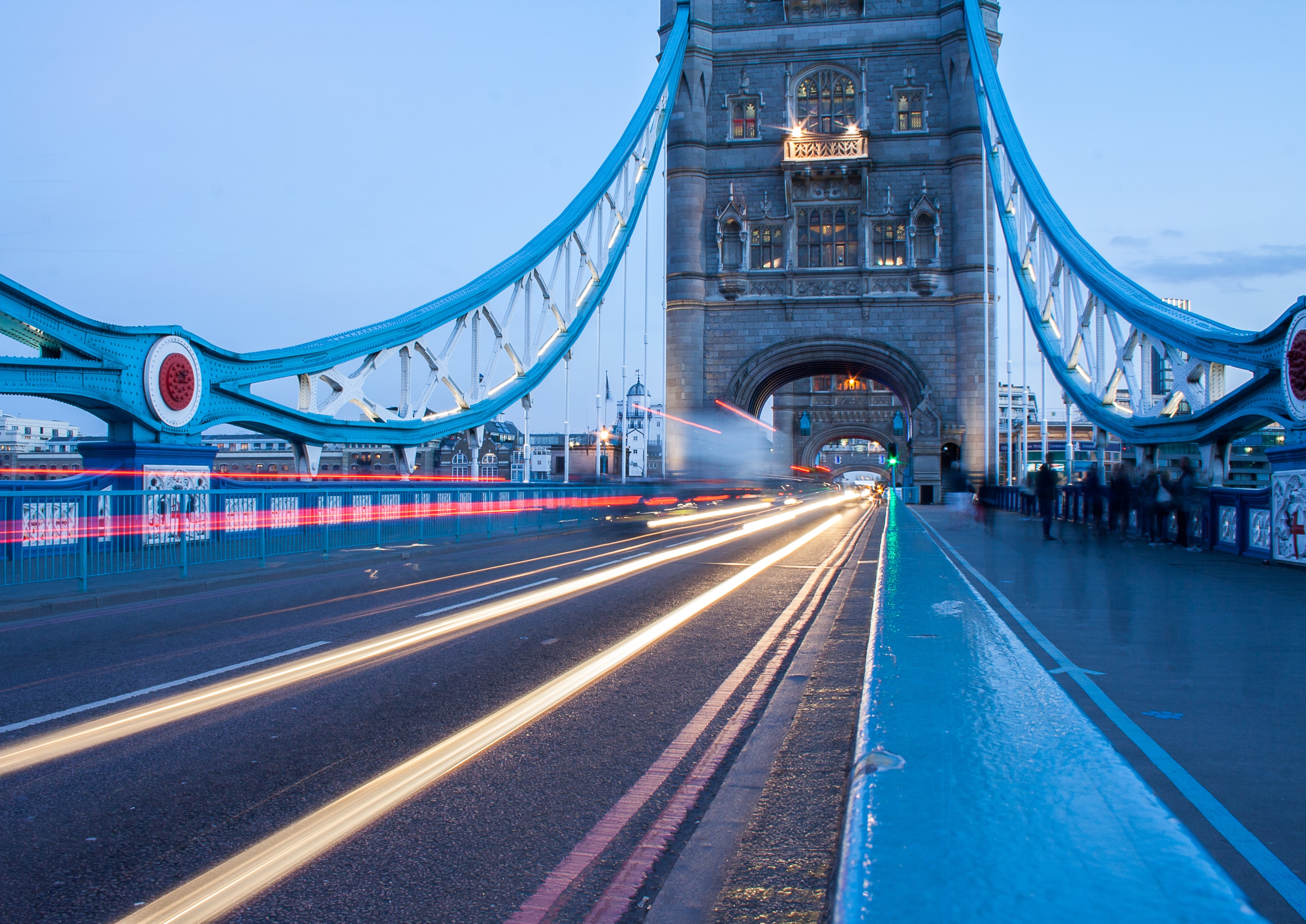 Traffic trails on London Tower Bridge at dusk, highlighting its iconic architecture.
