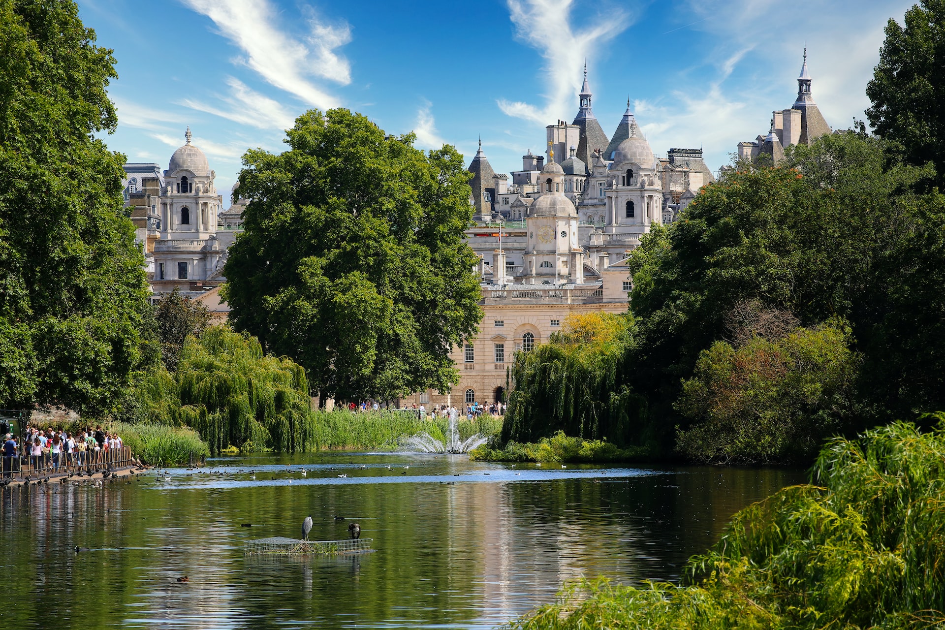 Hyde Park lake with trees and historic building in the background, London.