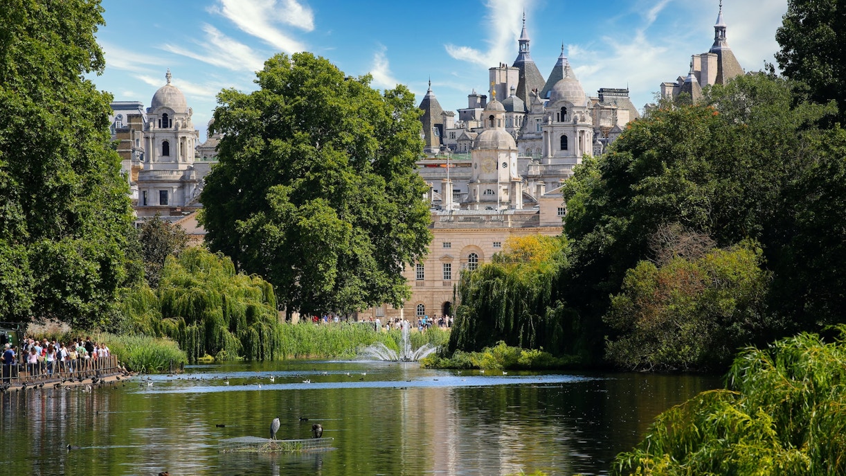 Hyde Park lake with trees and historic building in the background, London.