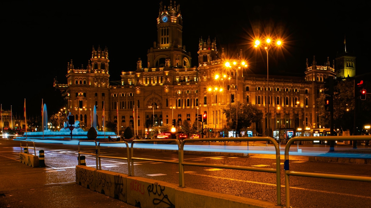Plaza de Cibeles in Madrid illuminated at night with traffic lights and fountain.