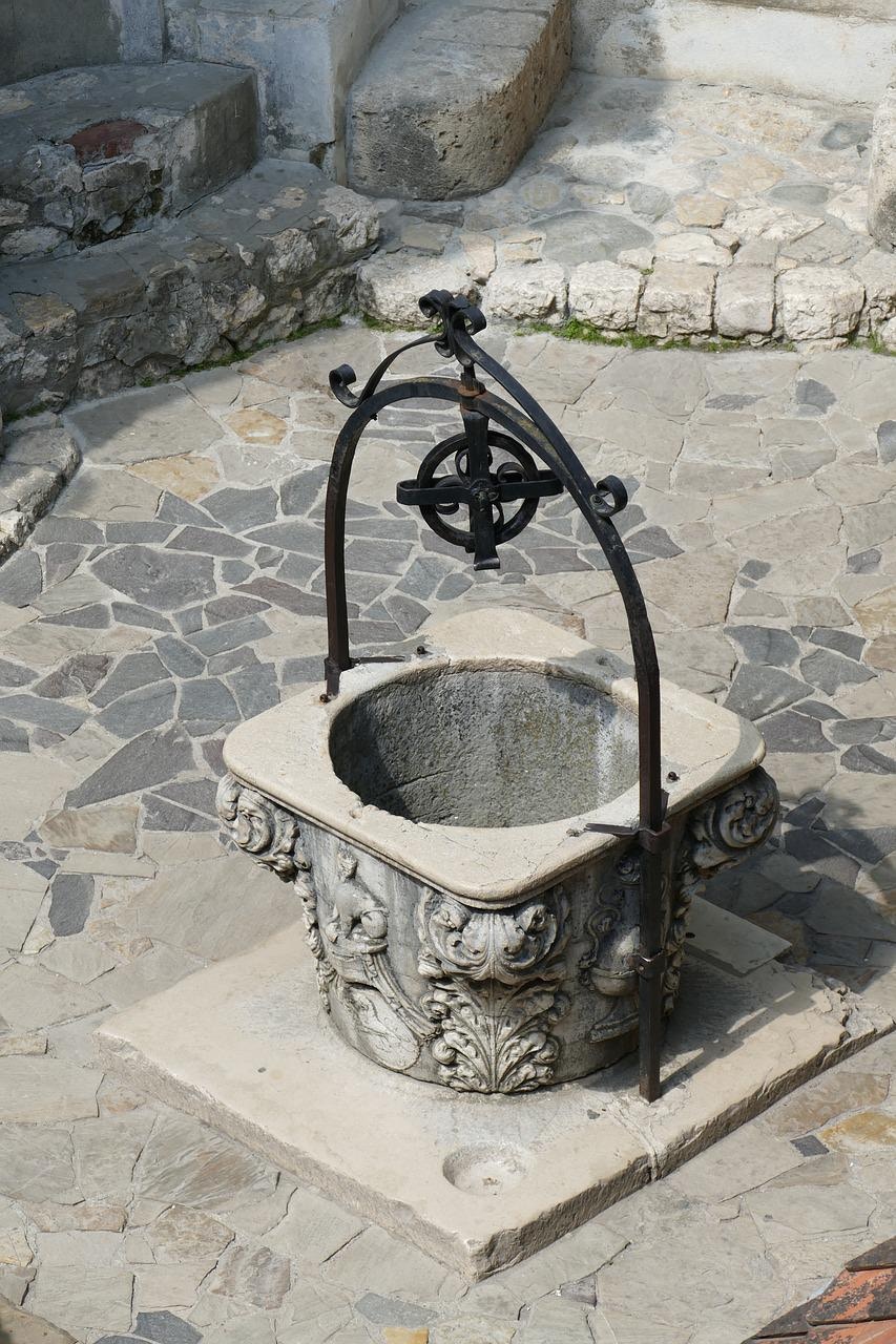 Stone well with ornate carvings at Bran Castle courtyard, Romania.
