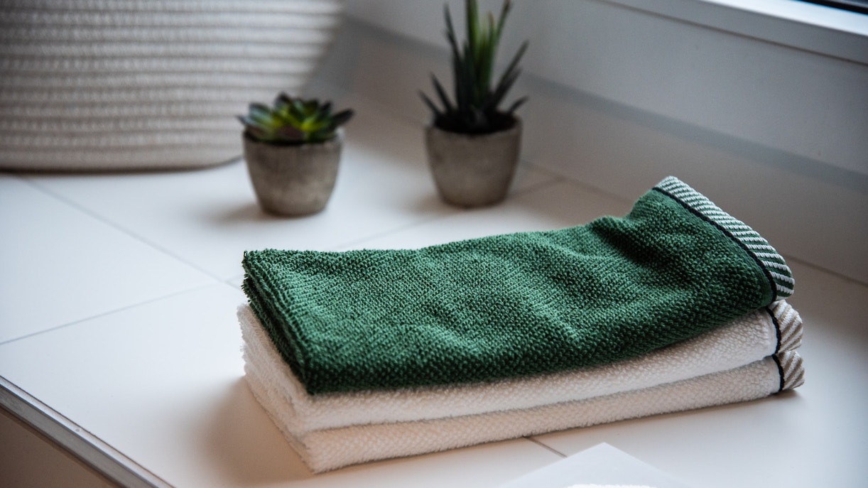 Green and white bath towels on a white surface with small potted plants, Barcelona in December.