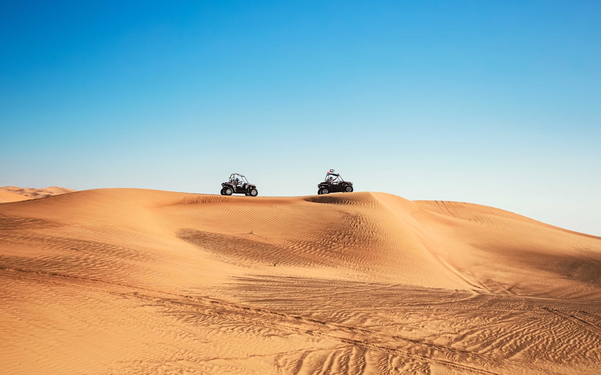 Dune buggies driving over sand dunes in Al Aweer Desert, Dubai Desert Safari.