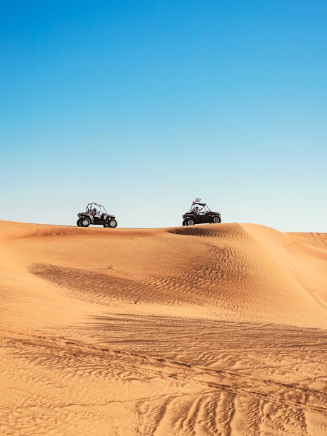 Dune buggies driving over sand dunes in Al Aweer Desert, Dubai Desert Safari.