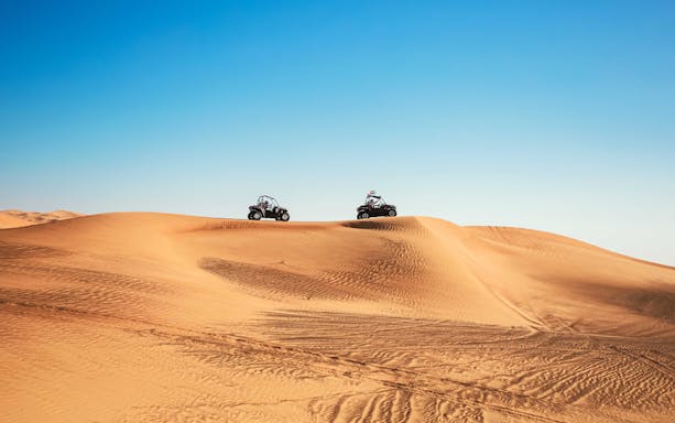 Dune buggies driving over sand dunes in Al Aweer Desert, Dubai Desert Safari.