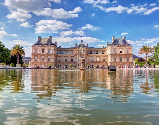 Jardin du Luxembourg in Paris with people strolling and relaxing near the central fountain.
