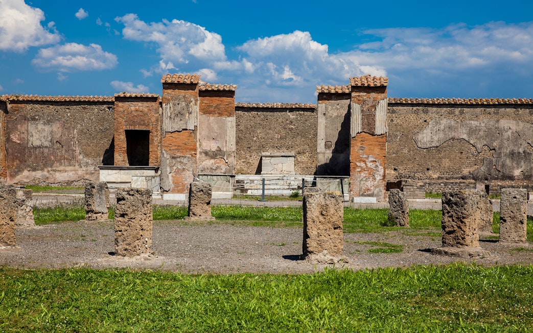 Remains of the Macellum in the Pompeii Forum, featuring ancient stone columns and brick structures.