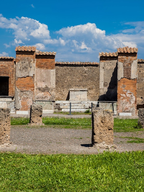 Remains of the Macellum in the Pompeii Forum, featuring ancient stone columns and brick structures.