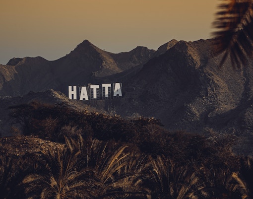 Hatta mountains with large "HATTA" sign, view from Dubai to Hatta tour.