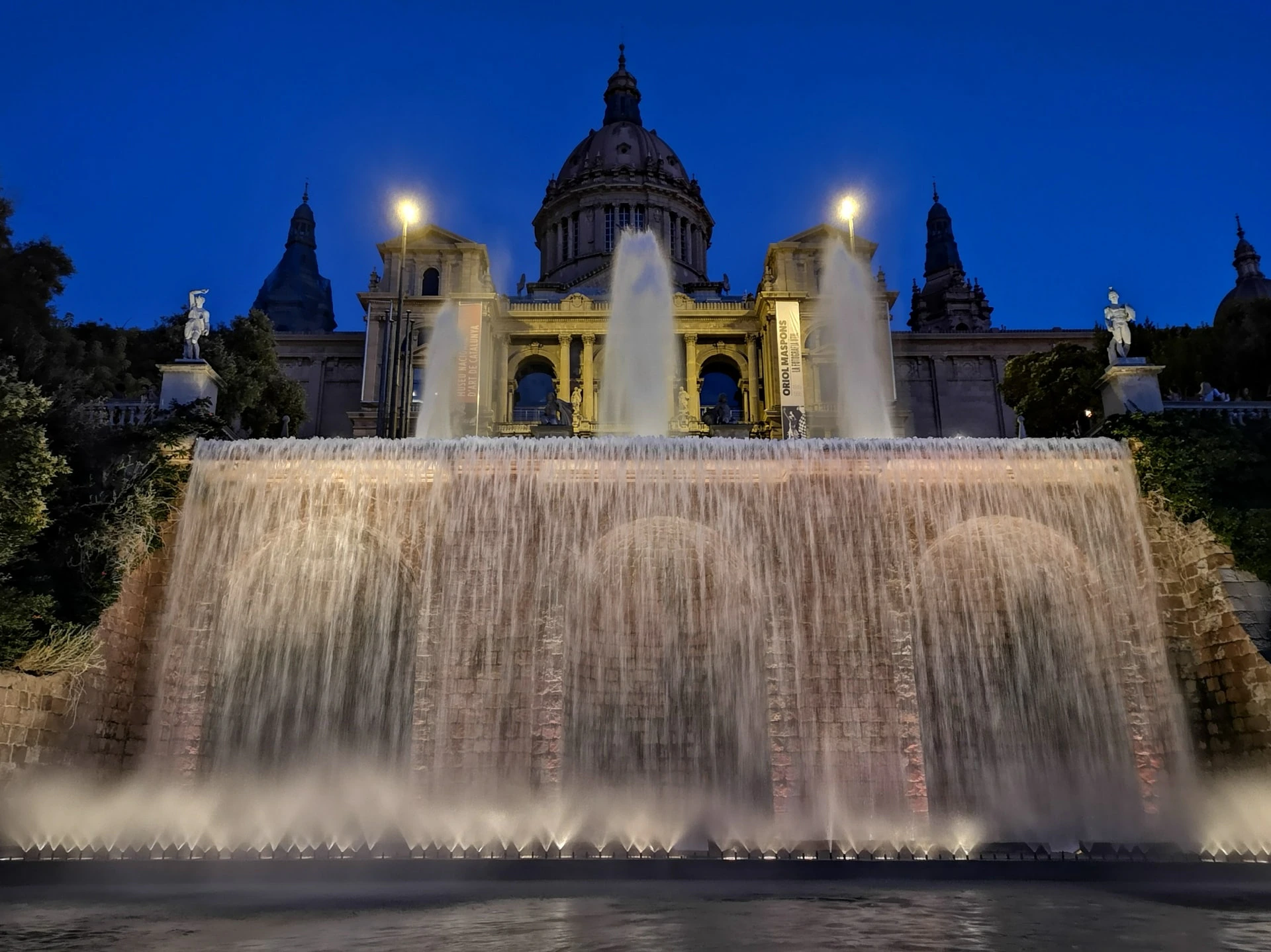 Front view of MNAC in Barcelona with illuminated fountains at night.