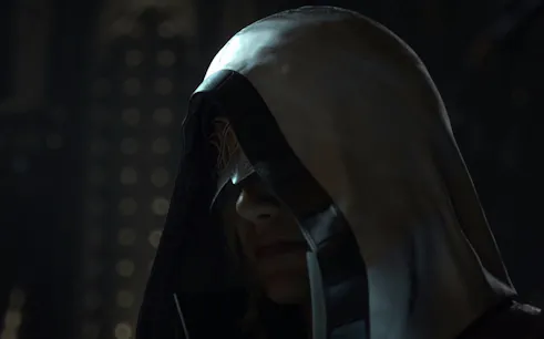 Hooded figure in dimly lit setting, related to "The Longest Con" tour.