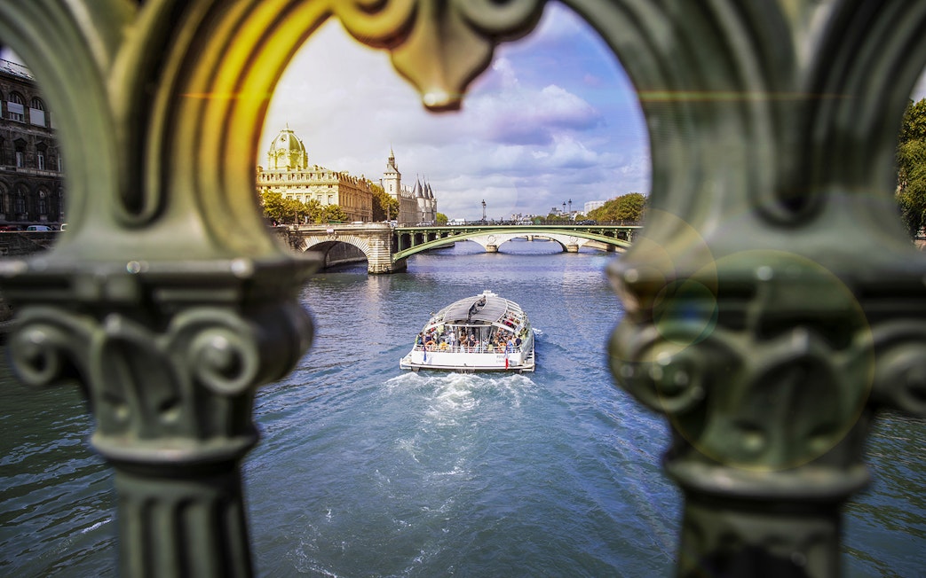 Batobus cruising on the Seine River in Paris with historic buildings and bridge in view.