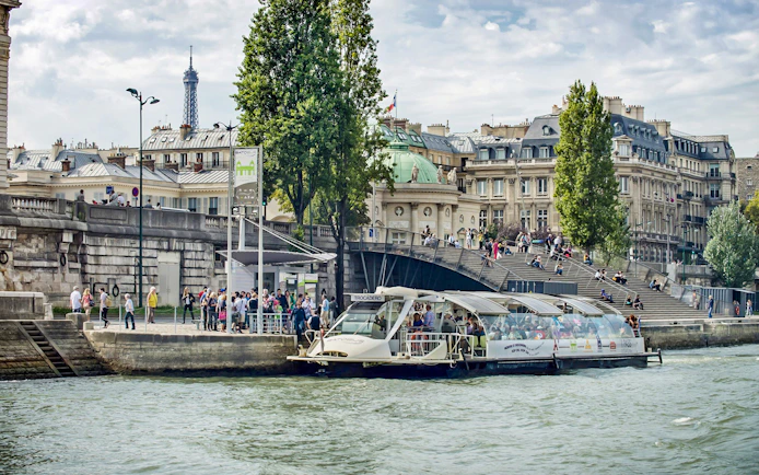 Batobus docked on the Seine River with Eiffel Tower in the background, Paris.
