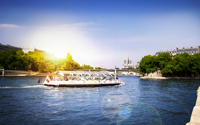 Batobus cruising on the Seine River with Notre-Dame Cathedral in the background, Paris.