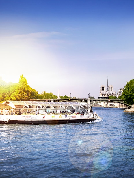 Batobus cruising on the Seine River with Notre-Dame Cathedral in the background, Paris.