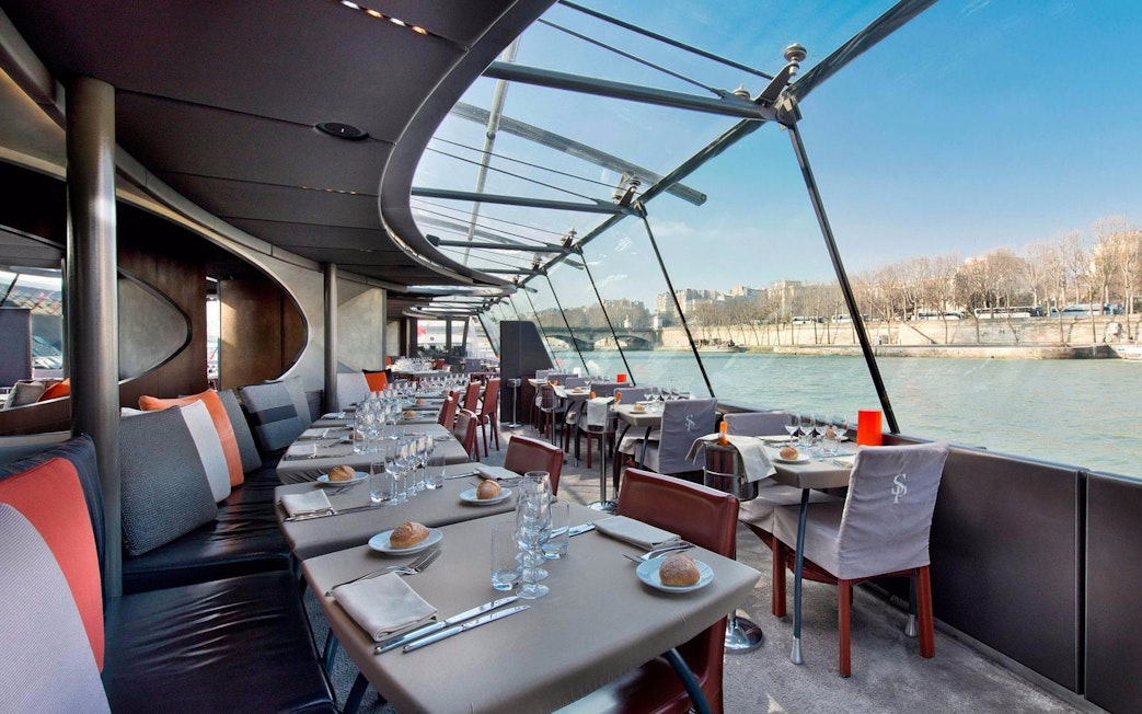 Seine River lunch cruise dining area with set tables and river view.