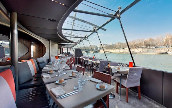 Seine River lunch cruise dining area with set tables and river view.