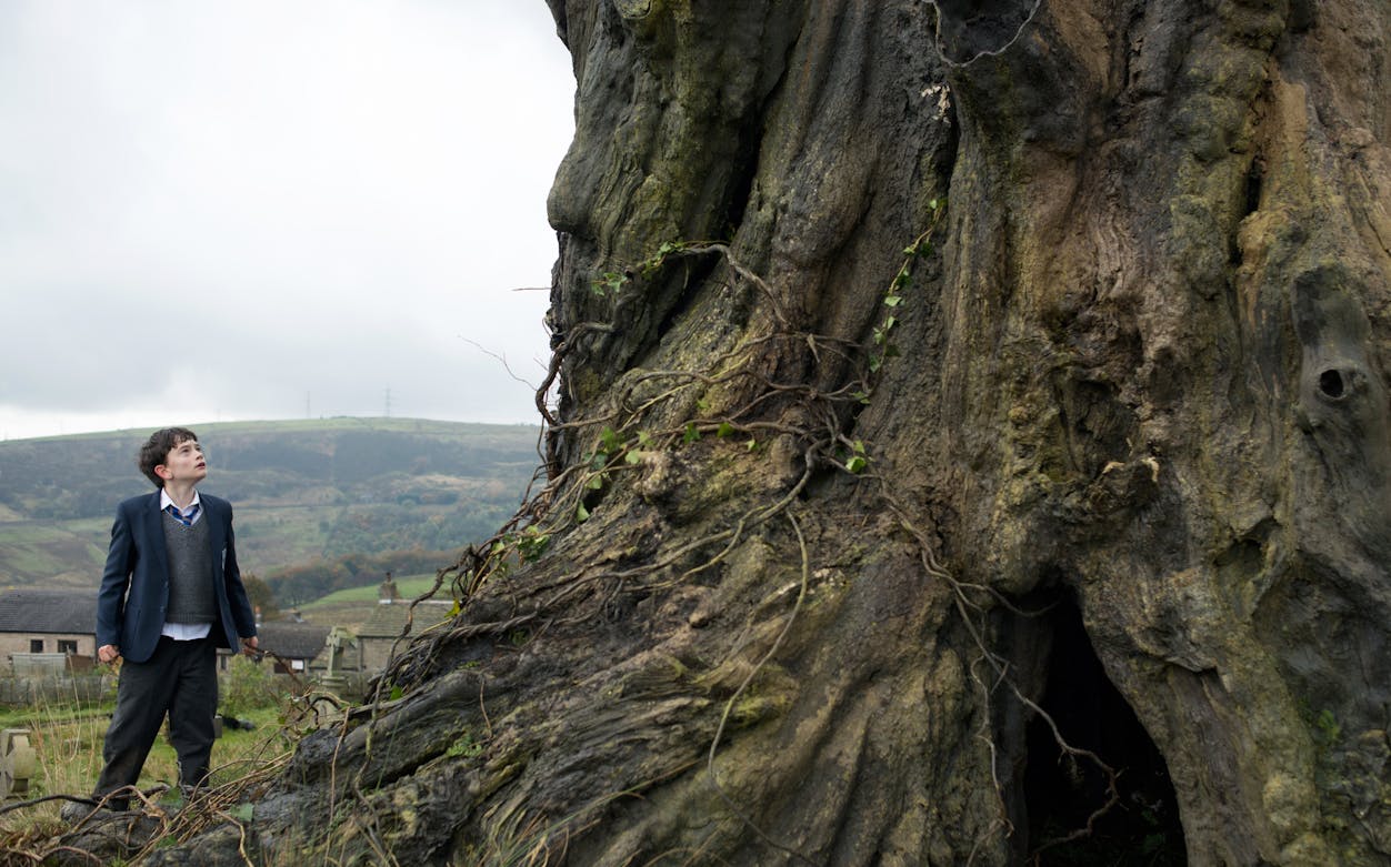 Stage performance of "A Monster Calls 2D" with actors in dramatic scene.