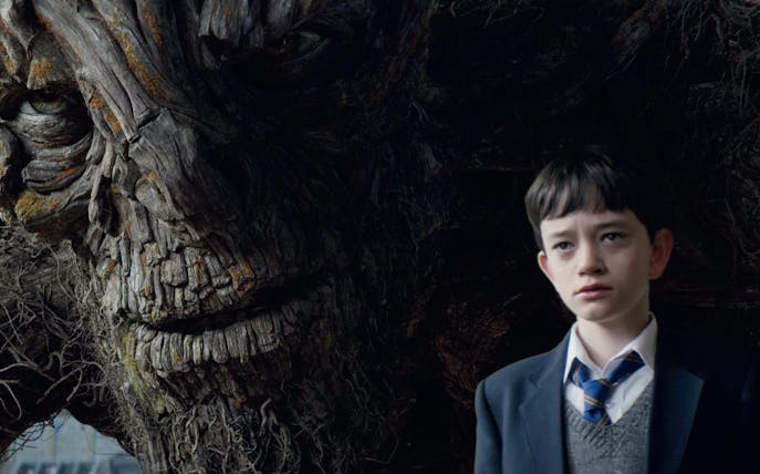 Boy standing next to a large tree-like creature from "A Monster Calls" 2D.