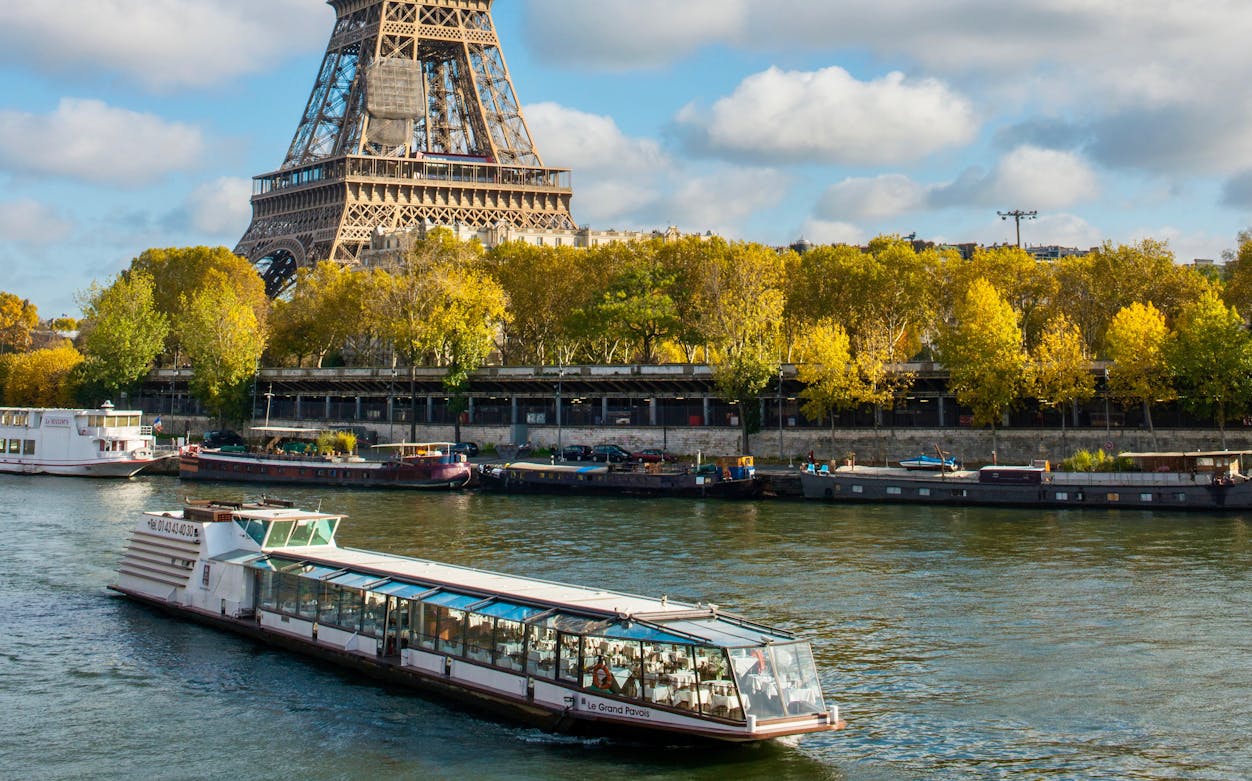 Seine River dinner cruise boat passing by the Eiffel Tower in Paris.