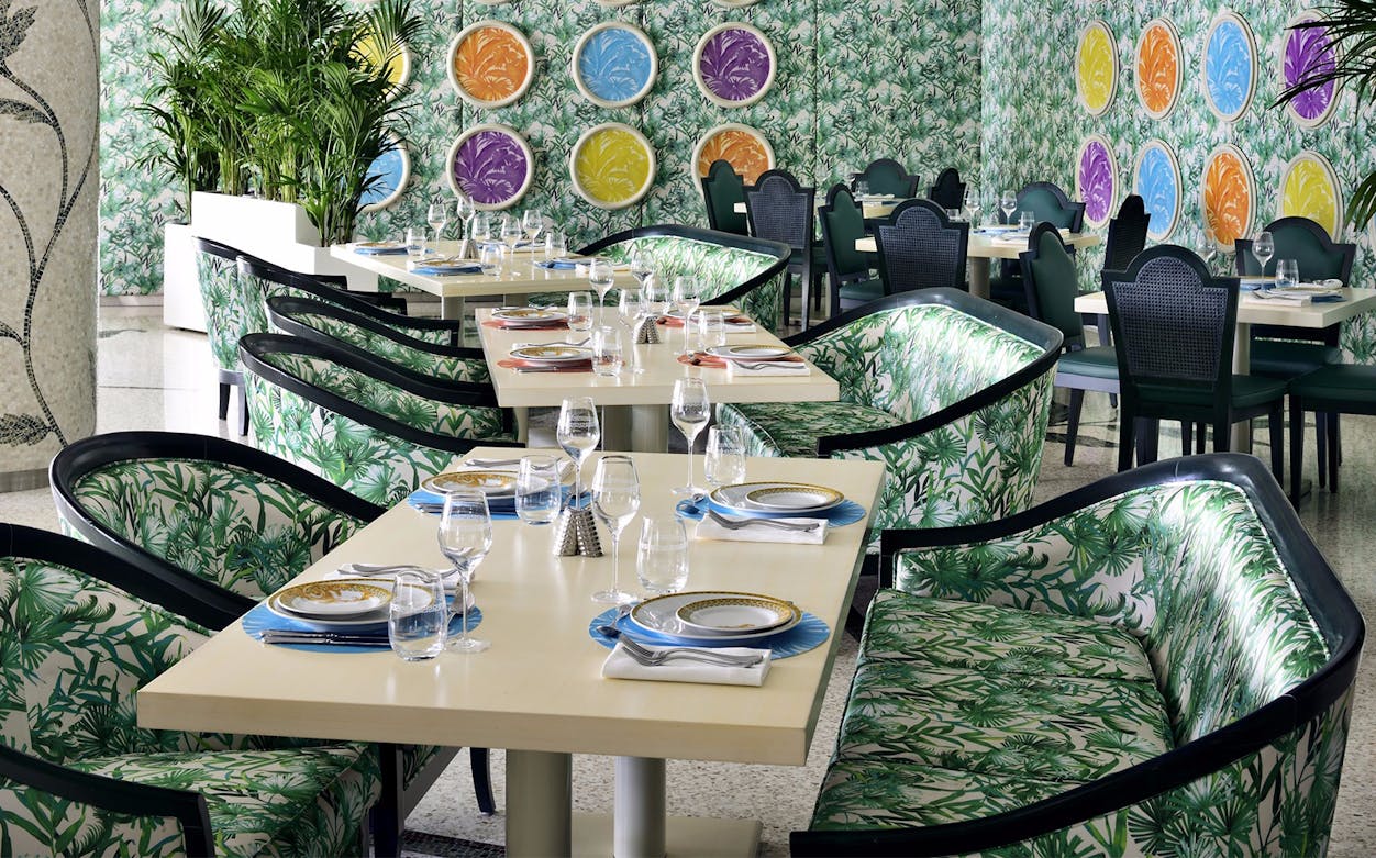 Dining setup at Giardino Restaurant, Palazzo Versace, with tropical-themed decor and elegant table settings.