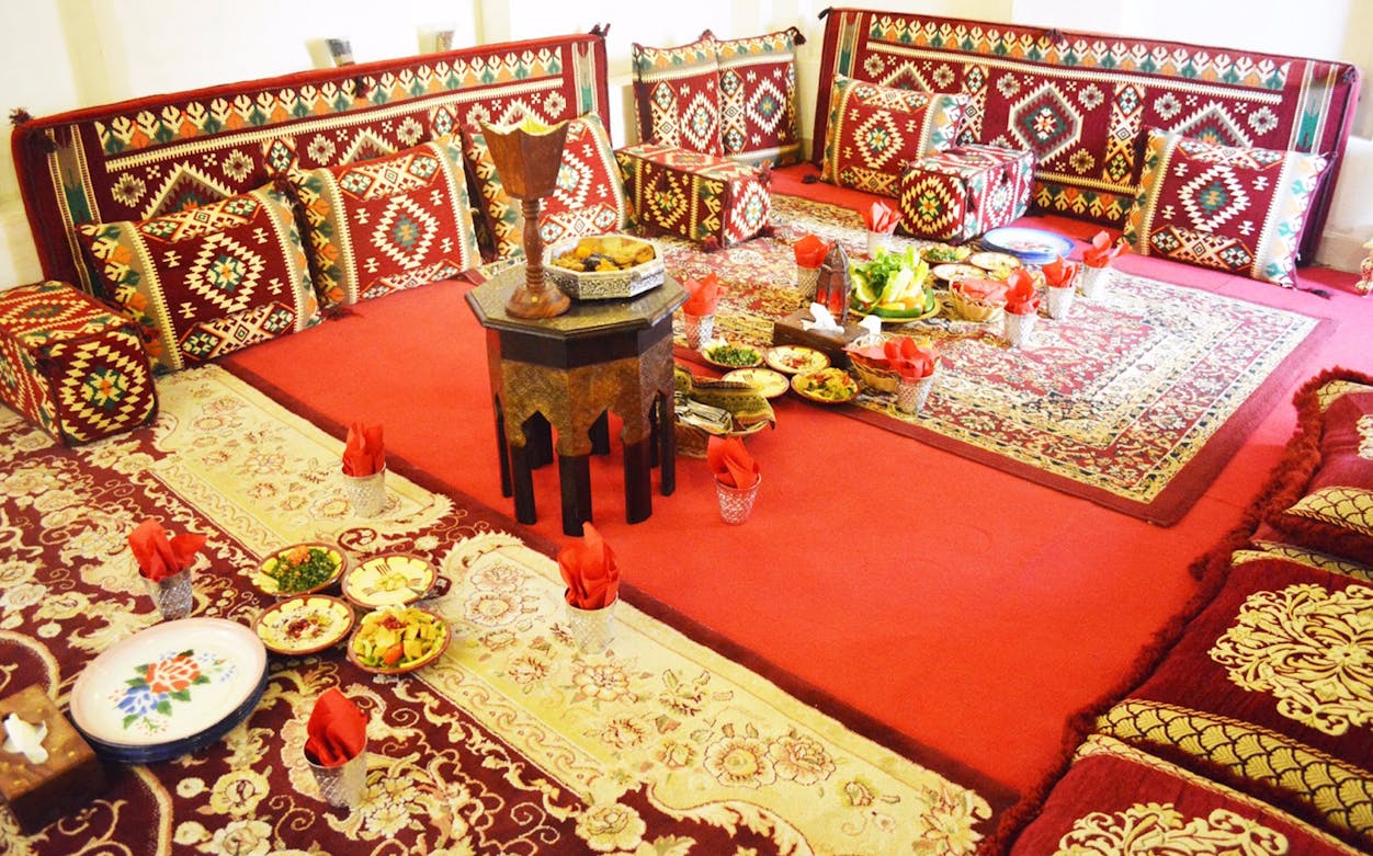 Traditional seating area with patterned cushions and a variety of dishes at Barjeel Al Arab, Barjeel Heritage Guest House.