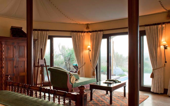 Interior of Al Maha Resort suite with desert view through large windows.