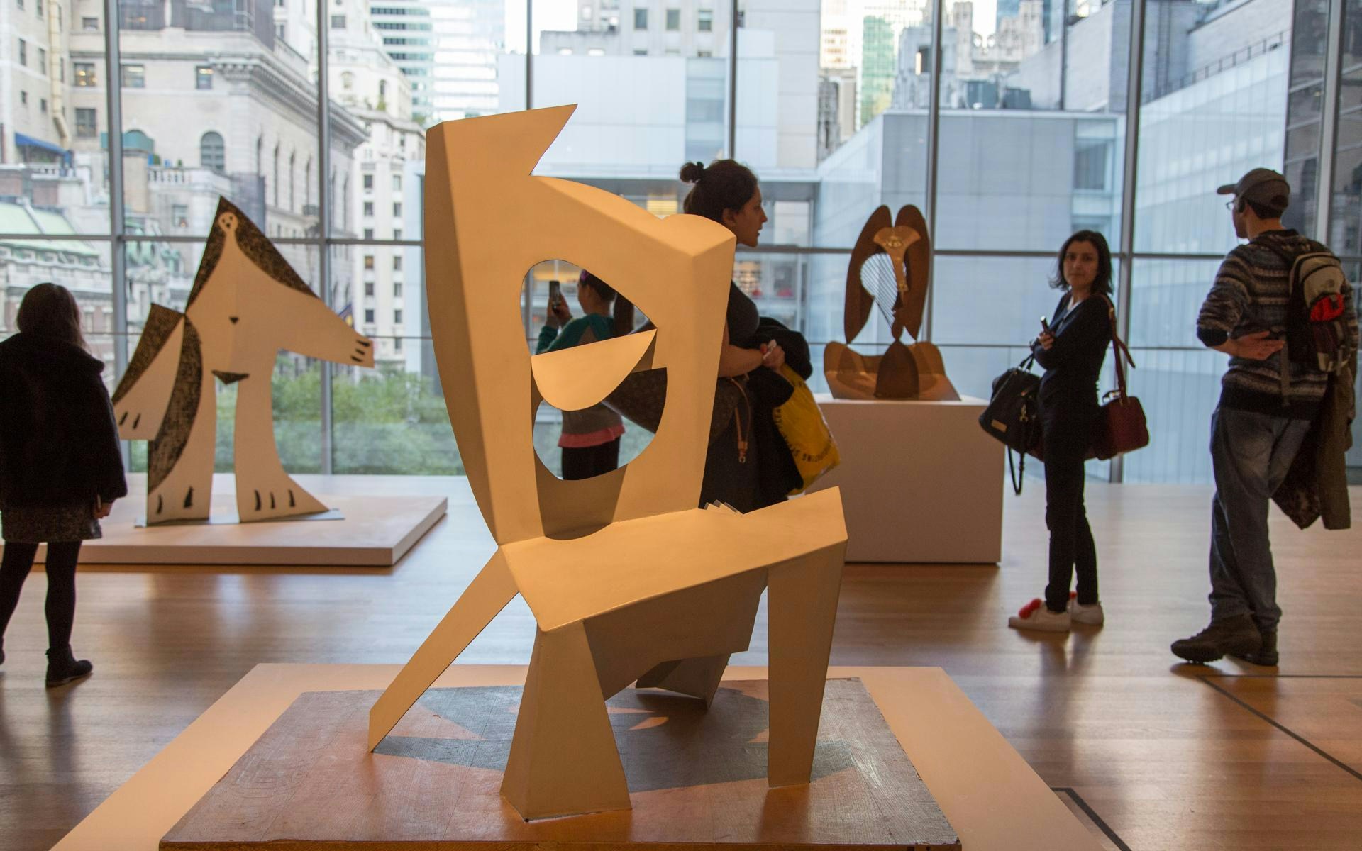 Sculptures on display at the Museum of Modern Art with visitors observing quietly.