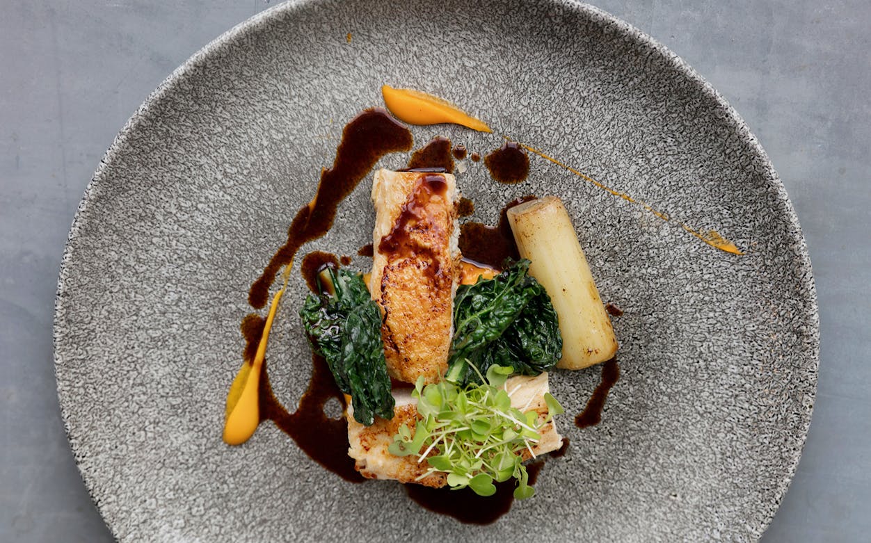 Gourmet dish served on Bateaux London Lunch Cruise, featuring chicken, greens, and sauce.