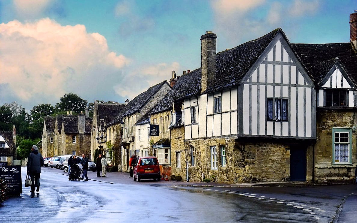 Lacock village street with historic stone and timber-framed buildings, part of Windsor Castle, Stonehenge, Lacock, and Bath tour.