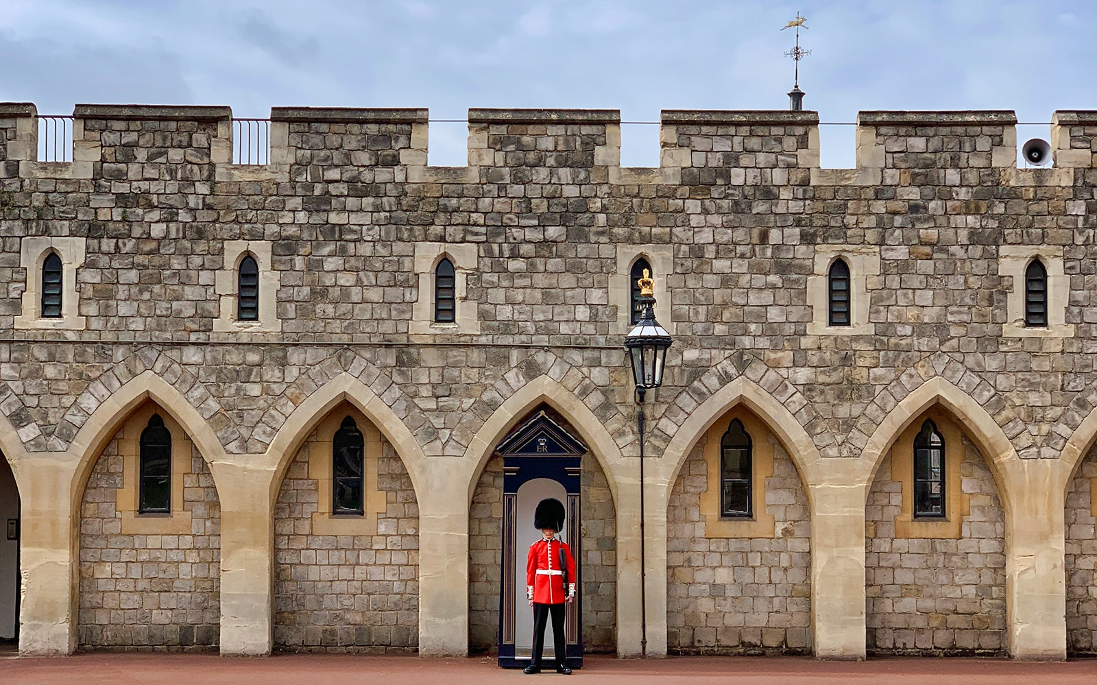 Guard in red uniform at Windsor Castle entrance, England.