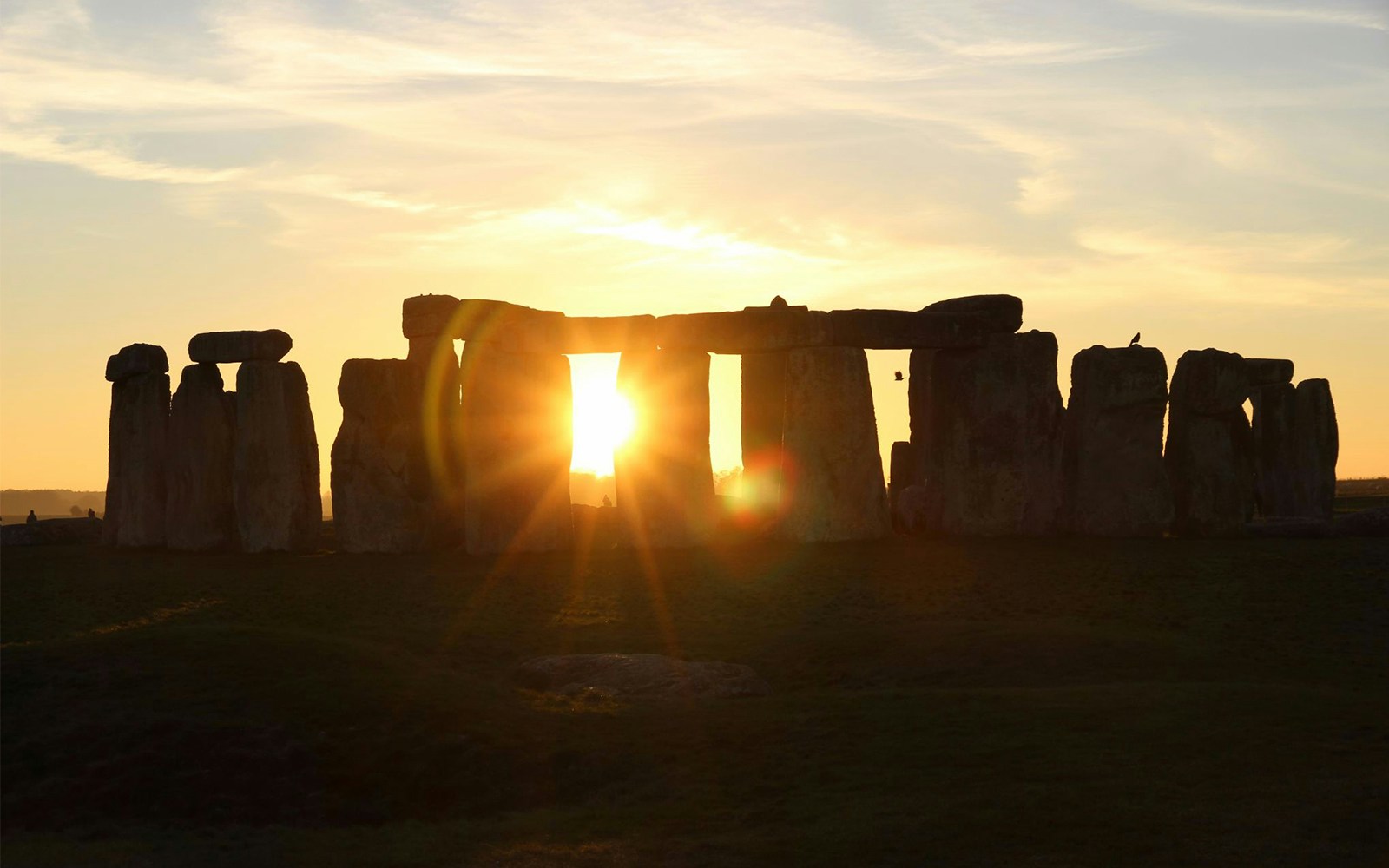 Stonehenge at sunset with sun rays through the stones, part of Discover Windsor, Oxford and Stonehenge tour.