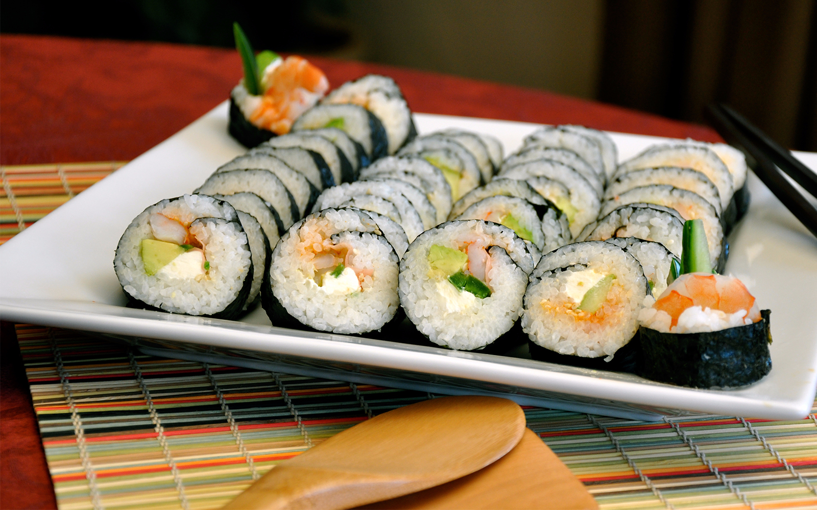 Sushi rolls with shrimp, avocado, and cream cheese on a white plate, part of a sushi making tour.