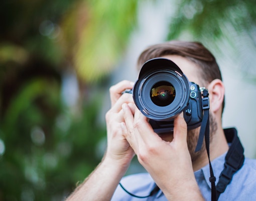 Person holding a DSLR camera, focusing on photography basics.