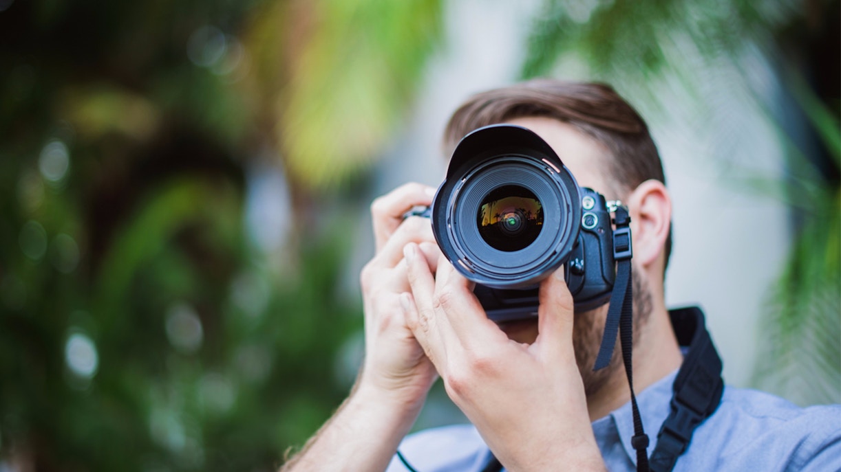 Person holding a DSLR camera, focusing on photography basics.