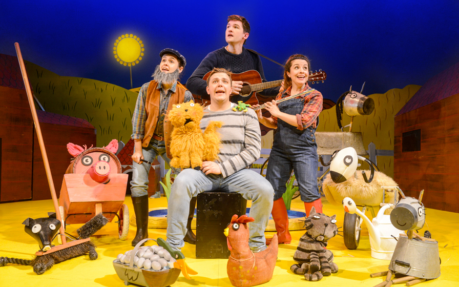 Actors performing "What The Ladybird Heard" with farm animal puppets on stage.