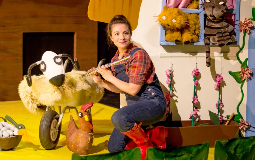 Children's theater performance of "What The Ladybird Heard" with colorful farm animal costumes.