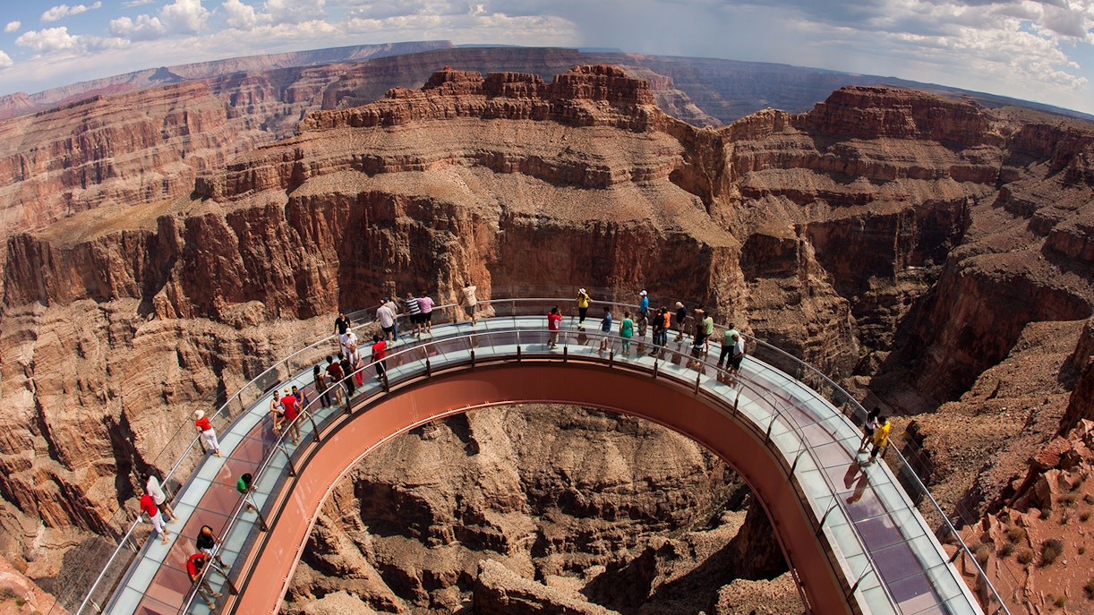 Tourists exploring the Grand Canyon West Rim by a luxury limo van under a clear blue sky
