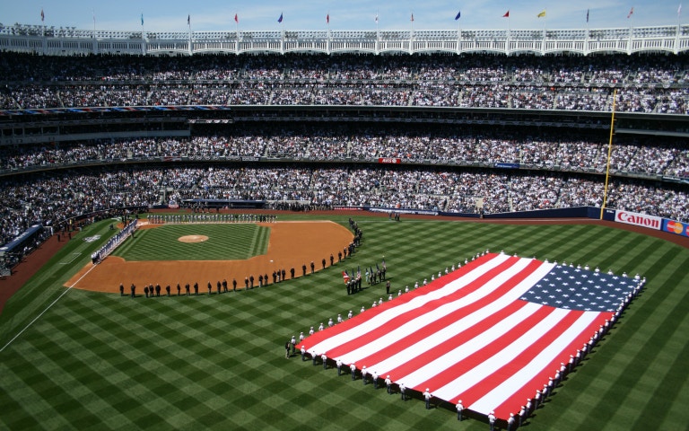 Baseball game at Yankee Stadium with large American flag on field, New York Yankees vs. Tampa Bay Rays.