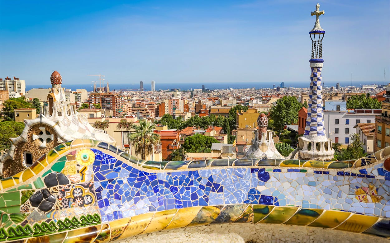 Park Güell mosaic bench with Barcelona cityscape in the background.