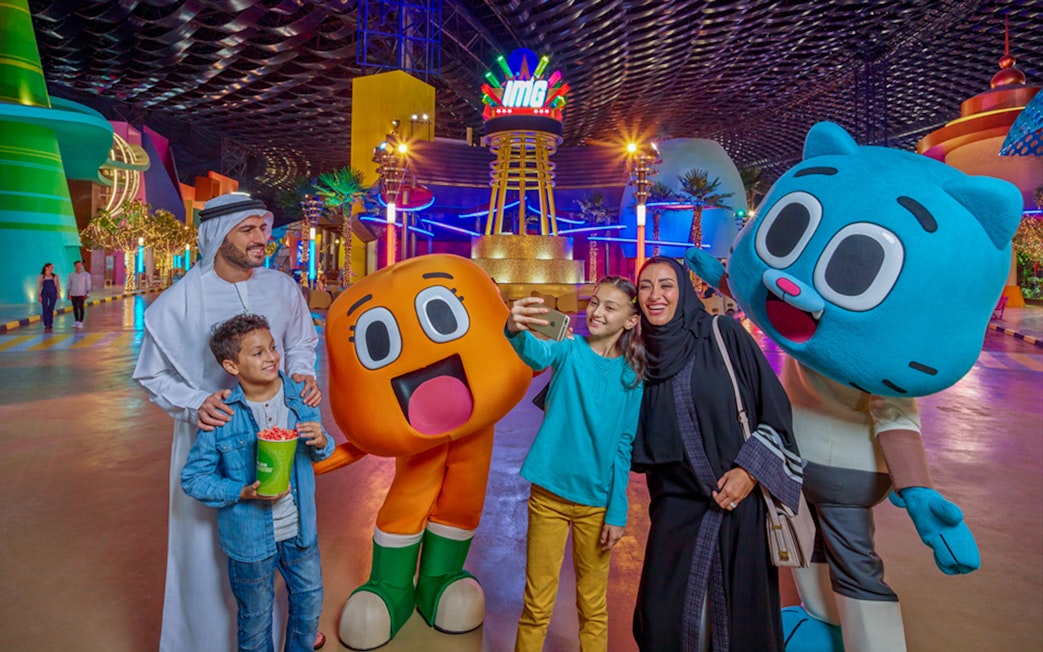 Visitors at IMG Worlds of Adventure entrance with cartoon characters in Dubai.