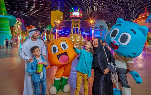 Visitors at IMG Worlds of Adventure entrance with cartoon characters in Dubai.