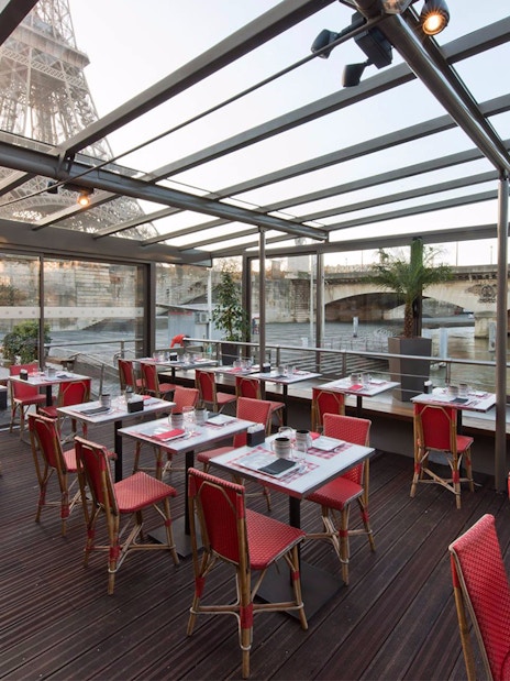 Le Bistro Parisien dining area with Eiffel Tower view, near Seine River, Paris.