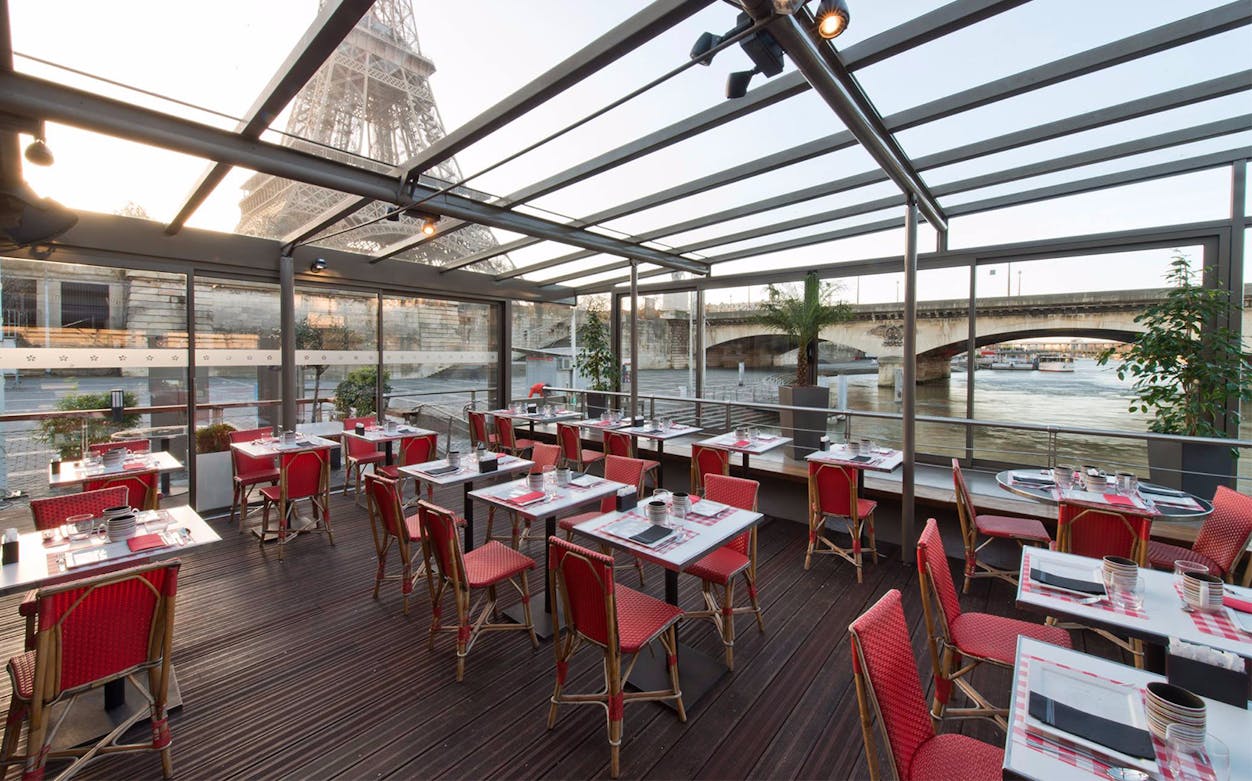 Le Bistro Parisien dining area with Eiffel Tower view, near Seine River, Paris.