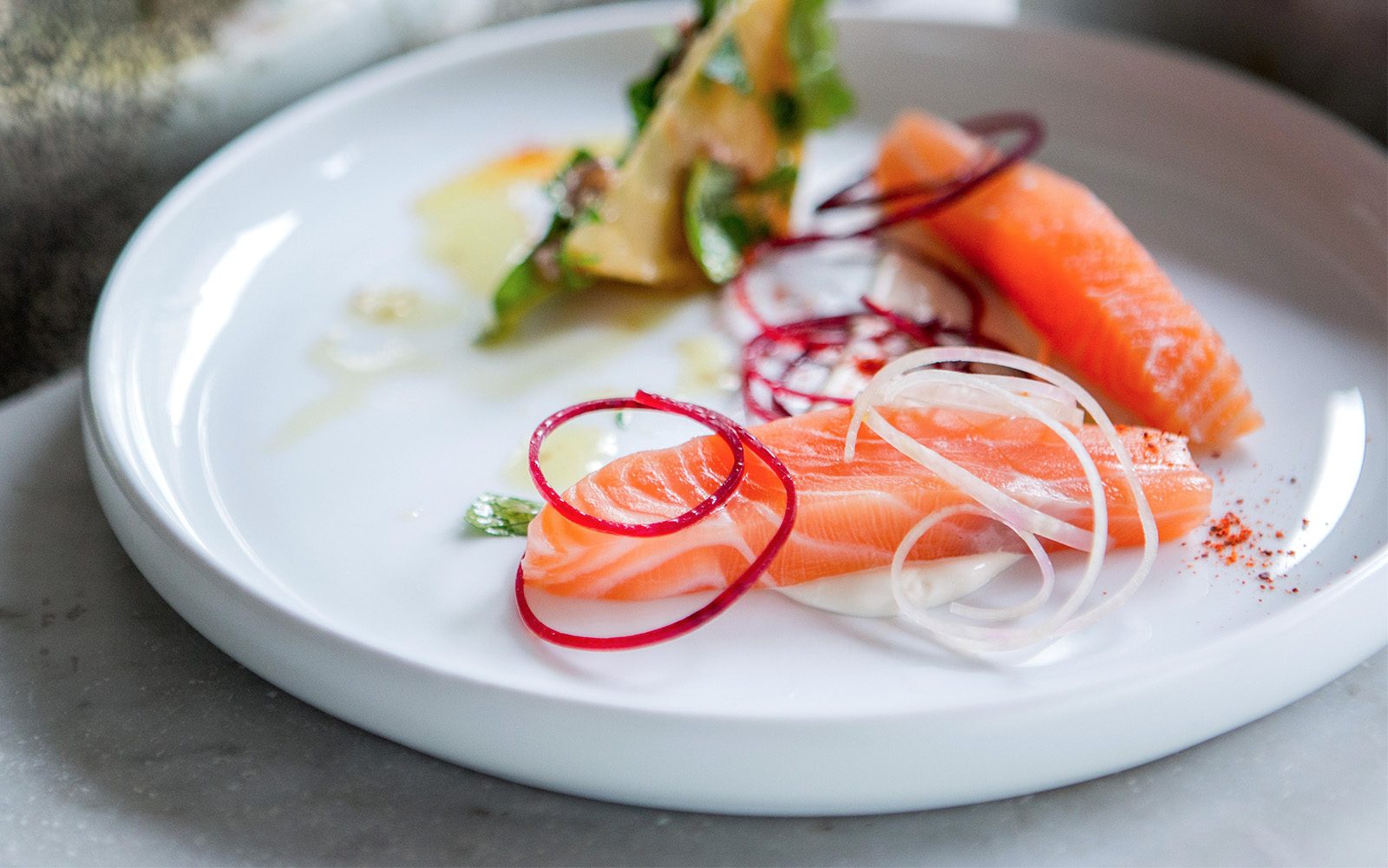 Salmon sashimi with garnishes on a white plate, Bateaux Parisien Bastille Day Dinner Cruise.