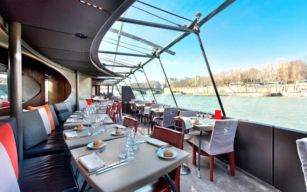 Dining setup on Bateaux Parisien cruise with Seine River view, Paris.