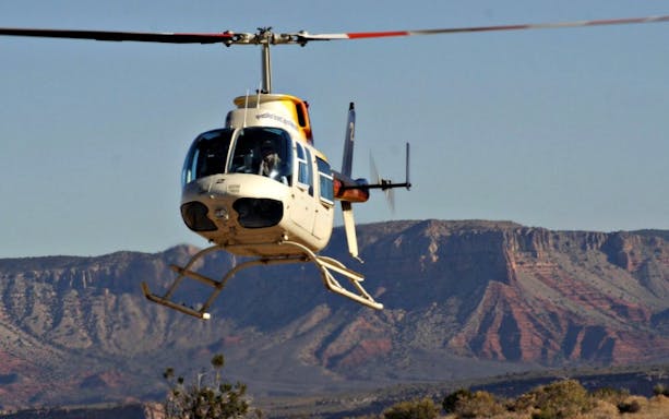 Helicopter flying over the Grand Canyon with scenic rock formations in the background.